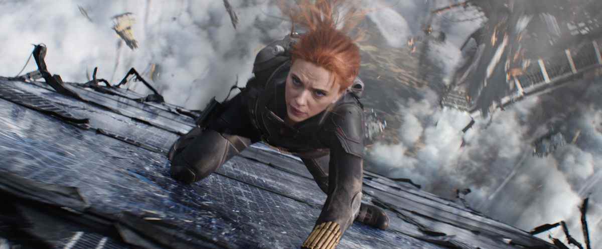 Black Widow glisse sur le côté d'un bâtiment au milieu des débris qui tombent dans le film Black Widow de Marvel Studios.
