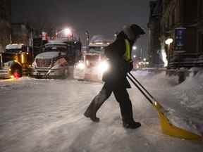 Un manifestant pellette la neige de la rue Wellington devant un blocus de camions alors qu'un avertissement de tempête hivernale est en vigueur, le 22e jour d'une manifestation contre les mesures COVID-19 qui s'est transformée en une manifestation antigouvernementale plus large, à Ottawa, le Vendredi 18 février 2022.