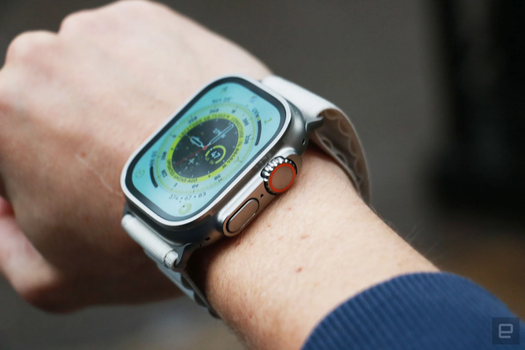 Vue hors angle de l'Apple Watch Ultra sur le poignet d'une personne, avec le cadran de la montre Wayfinder sur son écran.