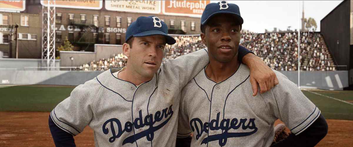 Deux hommes en tenue de baseball des Dodgers se tiennent côte à côte sur un terrain de baseball.