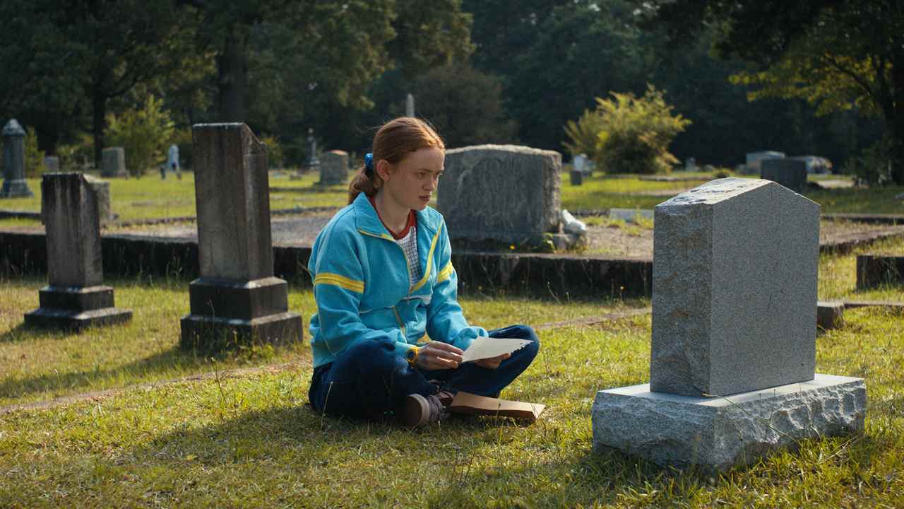 Max est assis devant la tombe de Billy pendant la journée dans la saison 4 de Stranger Things