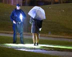 Un policier de Laval arrête une femme marchant sur le terrain de l'école après une fusillade dans un parc situé à côté du Collège Montmorency à Laval le vendredi 11 novembre 2022.