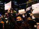 Des manifestants à Pékin tiennent des feuilles de papier blanc après une veillée pour les victimes d'un incendie à Urumqi, en Chine, le 28 novembre 2022. Les manifestations en cours en Chine vont bien au-delà des politiques draconiennes de COVID, écrit Sabrina Maddeaux.