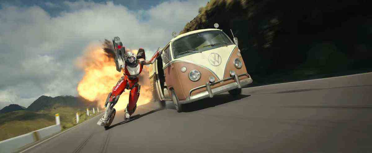 Acree le transformateur utilise ses pieds de moto pour chevaucher un bug VW marron loin d'une explosion lors d'une poursuite en voiture dans Transformers: Rise of the Beasts