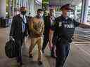 Un Henry Morales menotté est escorté en garde à vue après son atterrissage à l'aéroport international Pearson le mardi 15 septembre 2020.