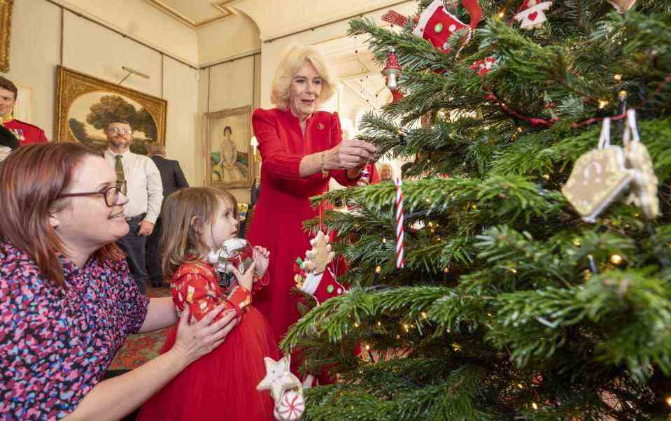 Camilla et un enfant décorent l'imposant sapin de Noël dans la salle du matin de Clarence House - Getty Images Europe
