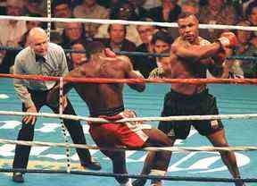 Mike Tyson (L) frappe le champion poids lourd WBC Frank Bruno (C) avec un coup de poing renversé au 3e tour le 16 mars au MGM Grand Garden.  L'arbitre Mills Lane (L) a appelé le combat au troisième tour pour donner à Tyson le titre WBC Heavyweight.  AFP PHOTO/Mike NELSON