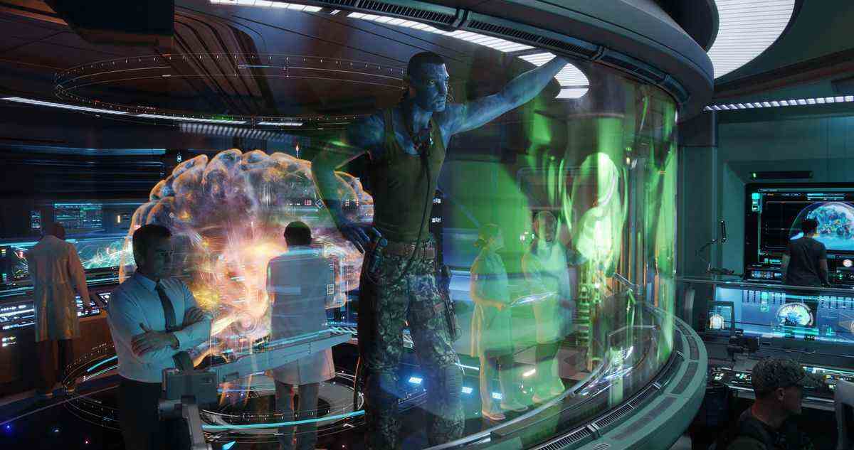 La forme Na'vi du colonel Quaritch (Stephen Lang) se tient dans un centre de commandement entouré d'humains et regarde un affichage VR élaboré dans Avatar: The Way of Water.