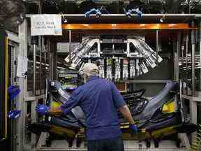 Un employé assemble un pare-chocs à l'usine de fabrication de pièces automobiles de Magna International Inc. Polycon Industries à Guelph, en Ontario.