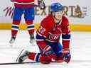L'ailier des Canadiens de Montréal Cole Caufield grimace après avoir subi un échec sévère de Trevor Lewis des Flames de Calgary lors de la deuxième période à Montréal le 12 décembre 2022.
