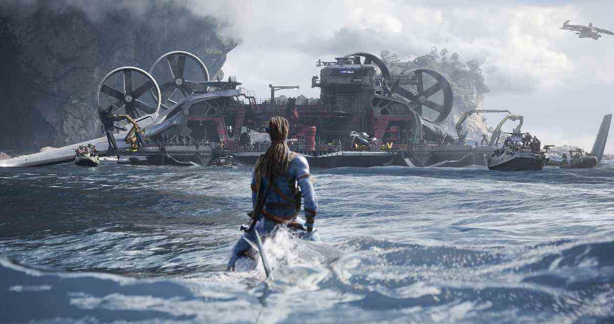 Un guerrier Na'vi assis au niveau de l'eau sur l'océan, chevauchant une créature marine submergée, est vu de dos, regardant un immense vaisseau humain mécanique recouvert de rotors et de moteurs dans un plan d'Avatar : la voie de l'eau