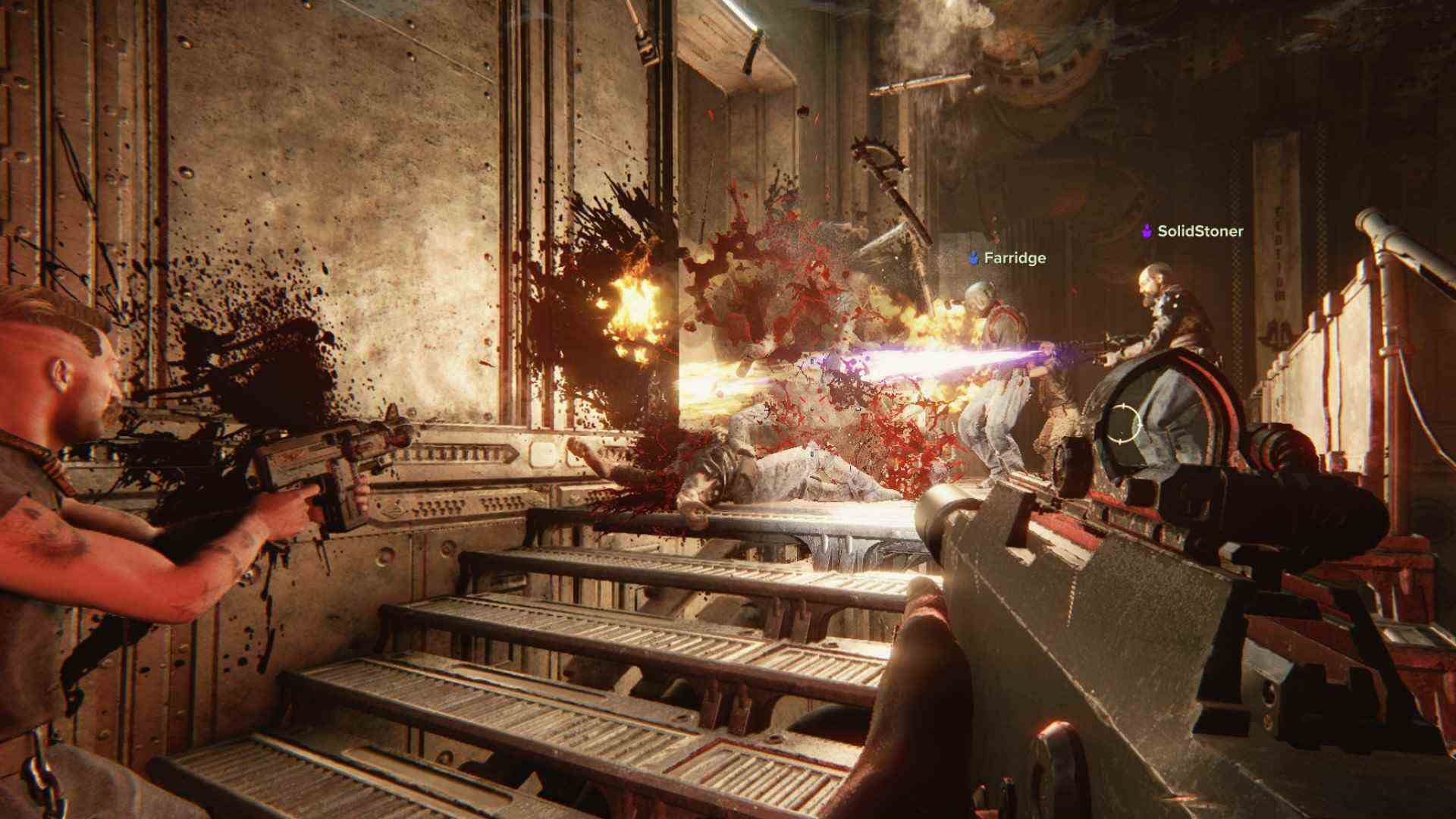 Revue de Warhammer 40k Darktide : Une escouade de joueurs tire des armes dans un couloir, alors que des éclaboussures de sang pleuvent sur les marches et les murs en métal
