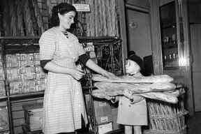 Sur cette photo d'archive prise le 24 novembre 1949, un petit garçon achète du pain baguette, alors que les Parisiens s'approvisionnent en pain pendant deux jours en préparation de la grève générale des boulangers à Paris.