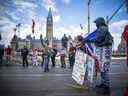 Divers manifestants et manifestants se tiennent sur la rue Wellington devant les édifices du Parlement à Ottawa, le 6 mars 2022.