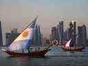 Des bateaux avec des voiles arborant les drapeaux des nations argentine et française naviguent devant la ligne d'horizon de Doha.
