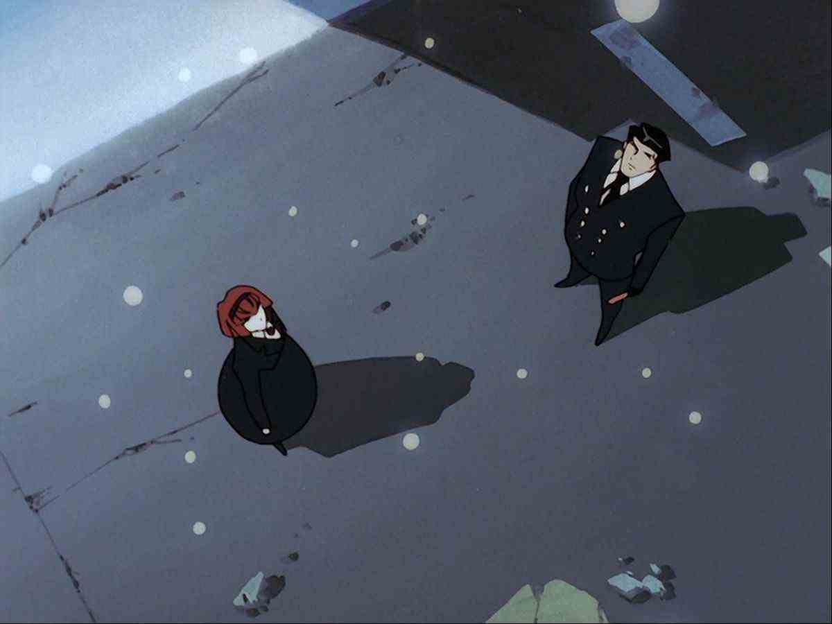 Un homme en costume noir et une jeune femme en robe noire lèvent les yeux alors que la neige tombe du ciel.
