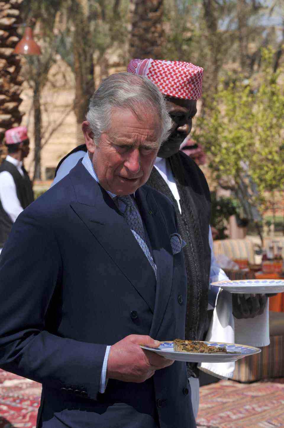 Le prince Charles de Grande-Bretagne tient une assiette devant un buffet lors d'une pause déjeuner le 19 février 2014 dans le cadre d'une visite sur un site historique à al-Diriyah, à la périphérie nord-ouest de la capitale saoudienne, Riyad.  Charles est en Arabie Saoudite en visite privée.  AFP PHOTO/ POOL / FAYEZ NURELDINE (Photo by Fayez Nureldine / POOL / AFP) (Photo by FAYEZ NURELDINE/POOL/AFP via Getty Images)
