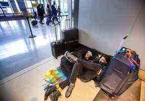 Aisha Osman (à gauche) et Dean Fellner qui se dirigent vers Los Angeles, utilisent leurs bagages pour se tailler un espace pour se reposer au niveau des départs du terminal 1 de l'aéroport international Pearson de Toronto le vendredi 23 décembre 2022.