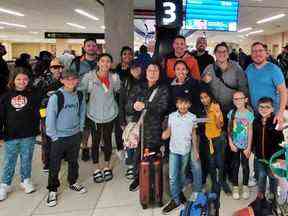 La famille Cody, à droite, pose avec d'autres passagers bloqués à Cancun, au Mexique, en raison d'annulations de vols par Sunwing après être revenus à Edmonton sur un vol nolisé.