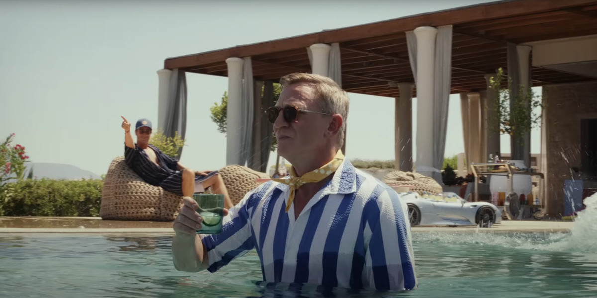 Daniel Craig dans le rôle de Benoit Blanc debout dans une piscine tenant un verre dans Glass Onion: A Knives Out Mystery
