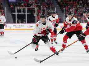 Le Canadien Connor Bedard, à gauche, patine devant l'Autrichien Lukas Horl, à droite, et Luca Auer lors de la deuxième période du Championnat mondial de hockey junior de l'IIHF à Halifax, le jeudi 29 décembre 2022.