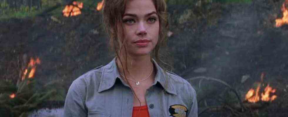 Denise Richards stands at an explosion site, looking annoyed in The World is Not Enough.