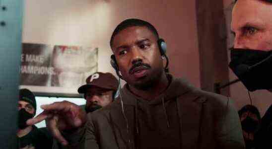 Michael B. Jordan pointing at a monitor and wearing headphones while directing Creed III