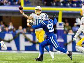 Le quart-arrière des Chargers de Los Angeles Justin Herbert (10) passe le ballon tandis que l'ailier défensif des Colts d'Indianapolis Kwity Paye (51) défend en seconde période au Lucas Oil Stadium le 26 décembre 2022 à Indianapolis.