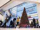 Les gens passent devant un grand arbre de Noël alors qu'ils font du shopping la veille de Noël dans un centre commercial à Ottawa en 2020.