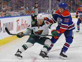 L'attaquant du Wild du Minnesota Kirill Kaprizov et les défenseurs des Oilers d'Edmonton Tyson Barrie se battent le long de la bande pour une rondelle libre au cours de la deuxième période à Rogers Place.