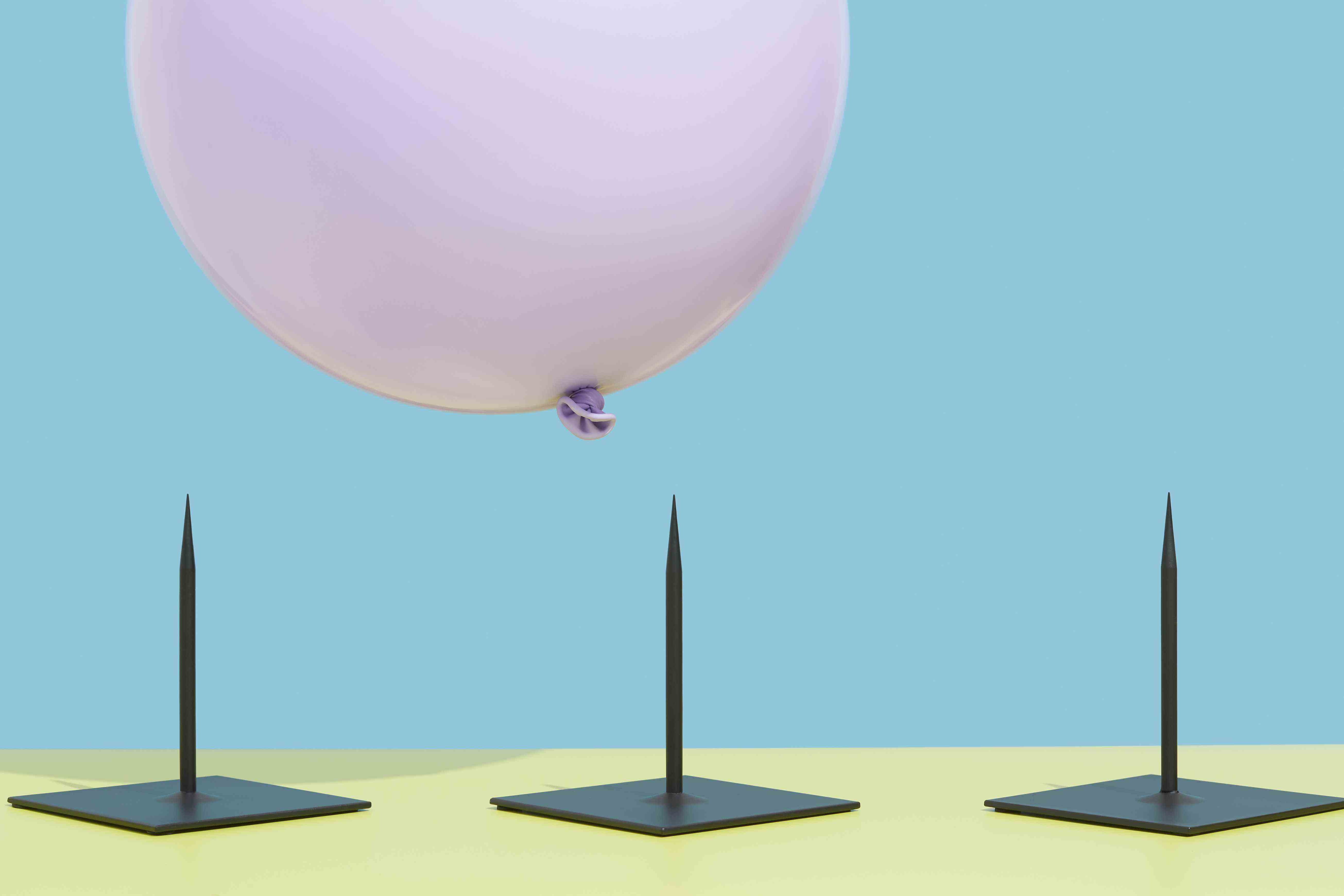 Image d'un ballon rose planant au-dessus de trois pointes pour représenter le risque.