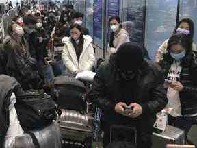 Les voyageurs entrants attendent pendant des heures pour monter à bord des bus pour partir pour les hôtels et les installations de quarantaine de l'aéroport de Guangzhou Baiyun, dans la province du Guangdong, dans le sud de la Chine, le 25 décembre 2022. La Presse canadienne/AP