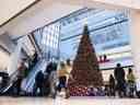 Les gens passent devant un grand arbre de Noël alors qu'ils font du shopping la veille de Noël dans un centre commercial à Ottawa en 2020.