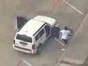 Capture d'écran d'un homme tenant un bébé dans un siège d'auto sortant d'un véhicule impliqué dans une poursuite policière.