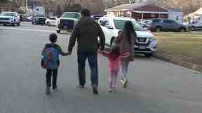 Des parents marchent avec des enfants devant l'école primaire de Richneck, où, selon la police, un garçon de six ans a blessé par balle un enseignant, à Newport News, en Virginie, le 6 janvier 2023, dans cette capture d'écran d'une vidéo à distribuer.
