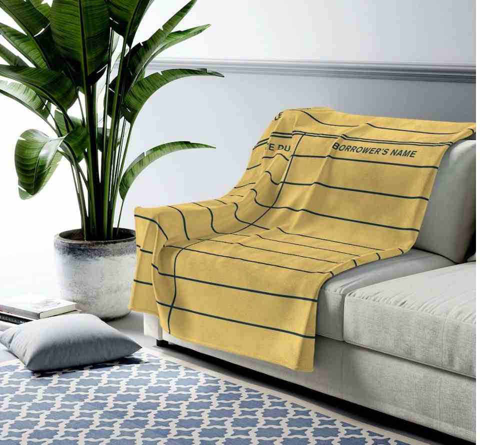 Image d'une couverture jaune conçue comme une carte de date d'échéance de bibliothèque sur un canapé gris. 