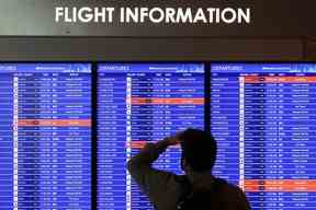 Un voyageur regarde un panneau d'information de vol à l'aéroport national Ronald Reagan de Washington le 11 janvier 2023 à Arlington, en Virginie.