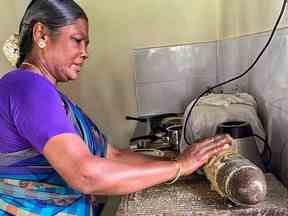 Un cuisinier local utilise un moulin à épices à l'hôtel Bangala à Karaikudi, Chettinad, Inde.  Donna Kennedy-Glans