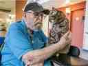 Warren McKay caresse Tig, un chat qui vit au Centre communautaire de Sherbrooke.  La présence constante mais contrôlée d'animaux fait partie de ce qui rend le foyer de soins de longue durée de Saskatoon unique.