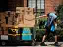 Un livreur d'Amazon.com Inc. tire un chariot de livraison rempli de colis à New York, aux États-Unis