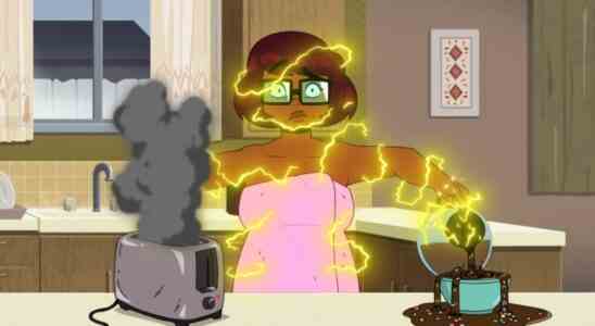Animated still of a teenage girl in glasses getting electrocuted as she handles a toaster while pouring coffee; still from "Velma"