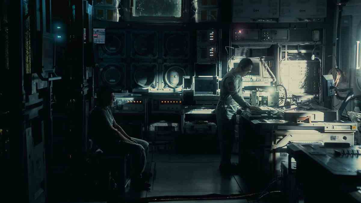 Un homme se penche sur une table pour regarder quelque chose dans un laboratoire scientifique sombre et futuriste dans The Wandering Earth II