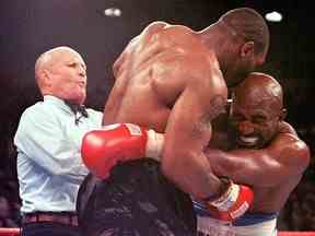 L'arbitre Lane Mills (L) intervient alors qu'Evander Holyfield (R) réagit après que Mike Tyson (C) se soit mordu l'oreille au troisième tour de leur combat de championnat WBA Heavyweight au MGM Grand Garden Arena de Las Vegas le 28 juin 1997.