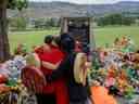 Dans cette photo d'archive prise le 4 juin 2021, des personnes de la nation crie de Mosakahiken s'embrassent devant un mémorial de fortune à l'ancien pensionnat indien de Kamloops pour honorer les 215 enfants dont les restes ont été découverts enterrés près de l'établissement, à Kamloops.