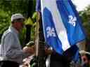 Un homme lève un drapeau alors que les gens protestent contre le nouveau projet de loi 21 du Québec, qui interdira aux enseignants, à la police, aux avocats du gouvernement et à d'autres personnes en position d'autorité de porter des symboles religieux tels que des couvre-chefs musulmans, des kippa et des turbans sikhs.