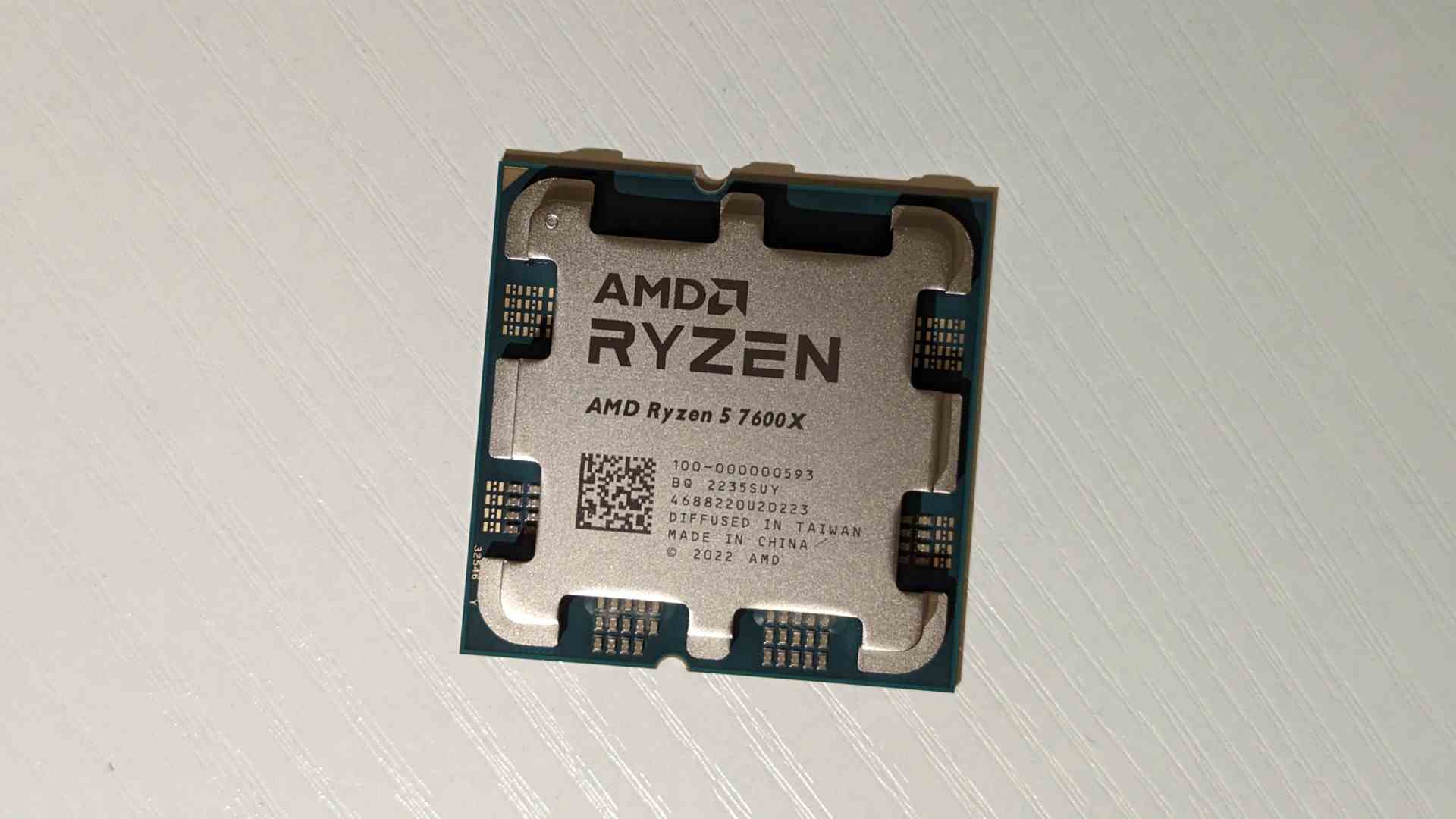 Le processeur AMD Ryzen 5 7600X posé sur une table en bois blanc