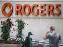 Des gens passent devant l'immeuble de Rogers Communications Inc. à Toronto.