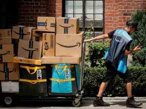 Un livreur d'Amazon.com Inc. tire un chariot de livraison rempli de colis à New York, aux États-Unis