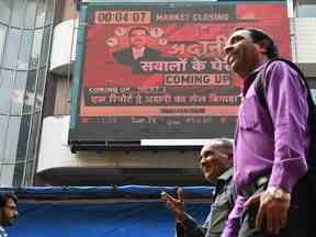 Les gens passent devant un tableau électronique affichant des informations sur le groupe Adani à la Bourse de Bombay à Mumbai le 27 janvier. après la publication du rapport sur les vendeurs à découvert.