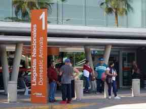 Les gens se tiennent devant l'aéroport international de Culiacan qui a été rouvert après avoir été fermé en raison de la violence causée par la détention du chef de gang de la drogue mexicain Ovidio Guzman, le fils de 32 ans du caïd emprisonné Joaquin 
